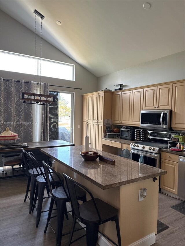 kitchen with a breakfast bar, stainless steel appliances, dark wood-type flooring, a center island, and hanging light fixtures