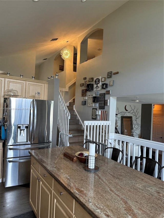 kitchen with cream cabinets, stainless steel fridge with ice dispenser, dark wood-type flooring, and light stone countertops