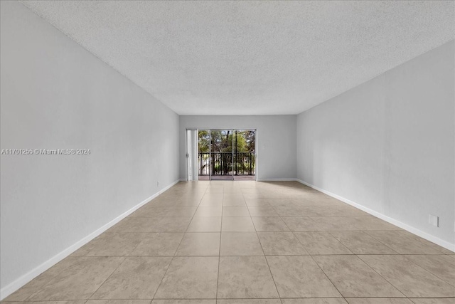 tiled empty room featuring a textured ceiling