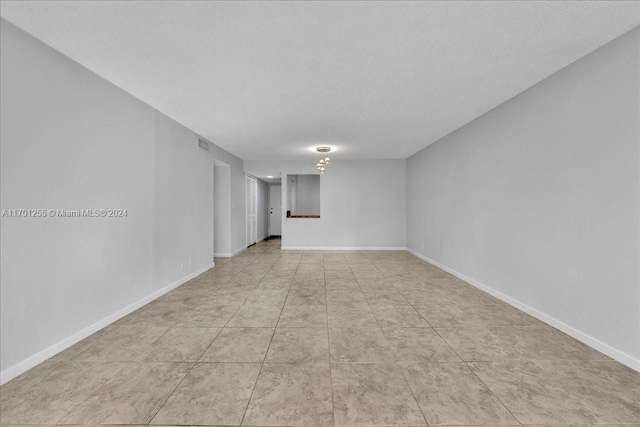 empty room with light tile patterned floors and a textured ceiling