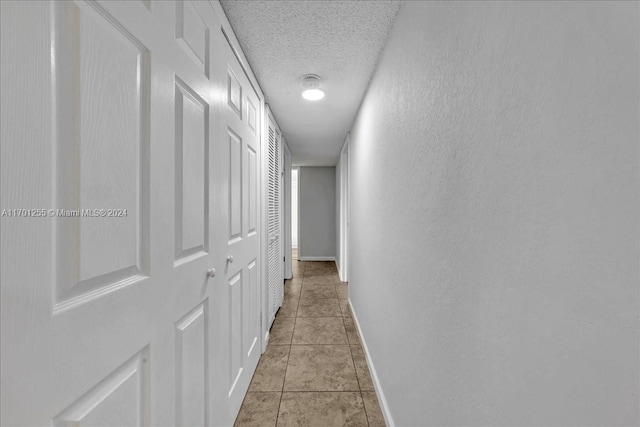 corridor with light tile patterned floors and a textured ceiling