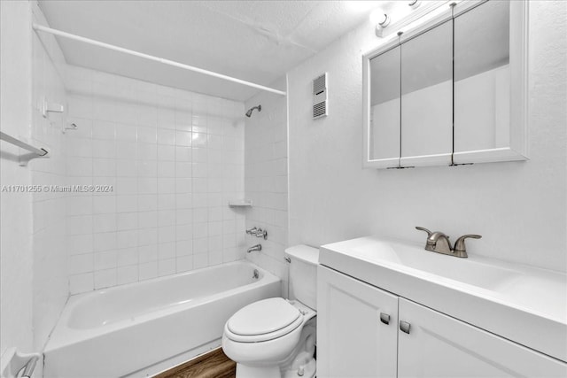 full bathroom featuring wood-type flooring, a textured ceiling, toilet, vanity, and tiled shower / bath