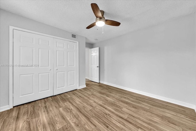 unfurnished bedroom featuring ceiling fan, a closet, a textured ceiling, and light hardwood / wood-style flooring