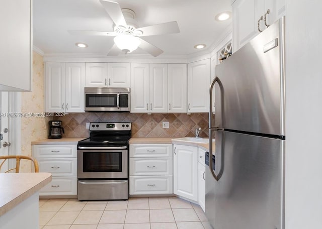 kitchen with white cabinets, ceiling fan, crown molding, and stainless steel appliances