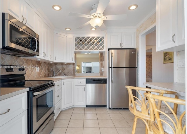 kitchen featuring appliances with stainless steel finishes, white cabinetry, ornamental molding, and sink