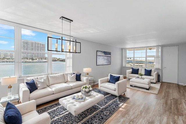 living room featuring a water view, hardwood / wood-style floors, and a notable chandelier