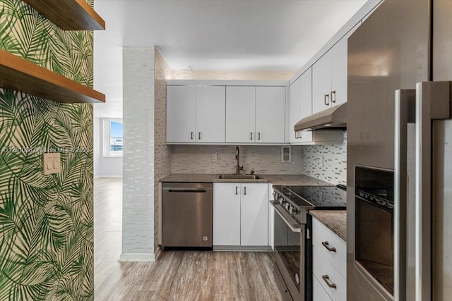 kitchen featuring sink, light hardwood / wood-style flooring, appliances with stainless steel finishes, white cabinetry, and backsplash