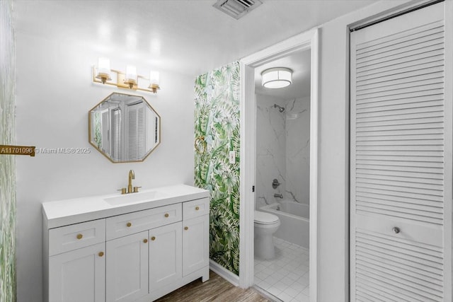 full bathroom with vanity, tiled shower / bath, and toilet