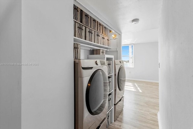 clothes washing area featuring light wood-type flooring and washer and clothes dryer