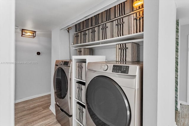 washroom with washing machine and clothes dryer and light wood-type flooring