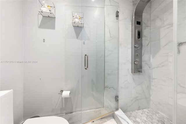 bathroom with a shower with shower door and toilet