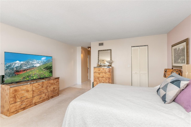 bedroom featuring light carpet, a textured ceiling, and a closet