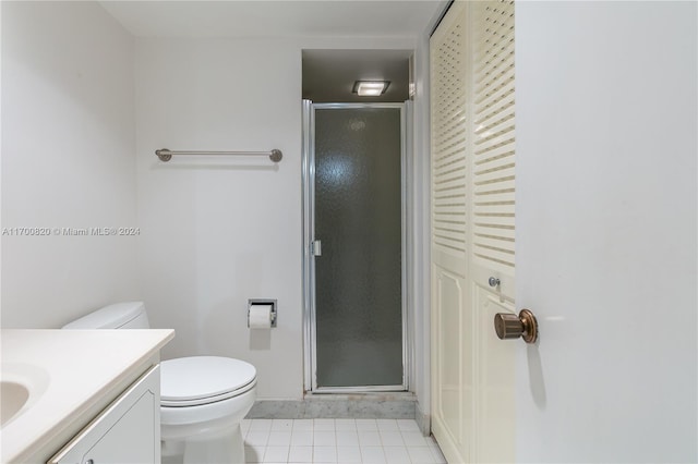 bathroom featuring tile patterned flooring, vanity, toilet, and an enclosed shower