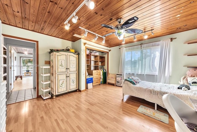 bedroom with multiple windows, ceiling fan, rail lighting, and hardwood / wood-style flooring