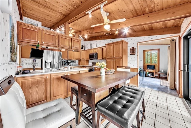 kitchen with rail lighting, ceiling fan, light tile patterned floors, beam ceiling, and stainless steel appliances