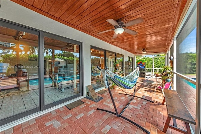 sunroom / solarium featuring ceiling fan, wooden ceiling, and a wealth of natural light