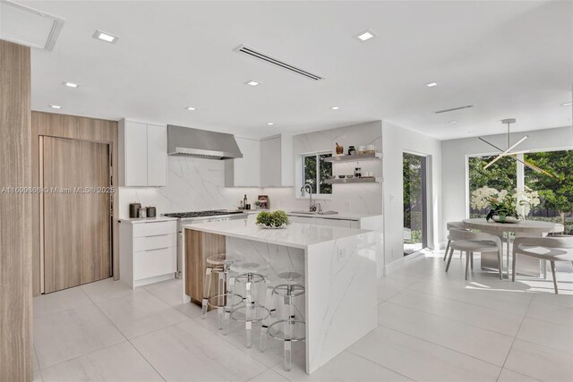 kitchen featuring sink, white cabinets, double oven range, a center island, and wall chimney exhaust hood