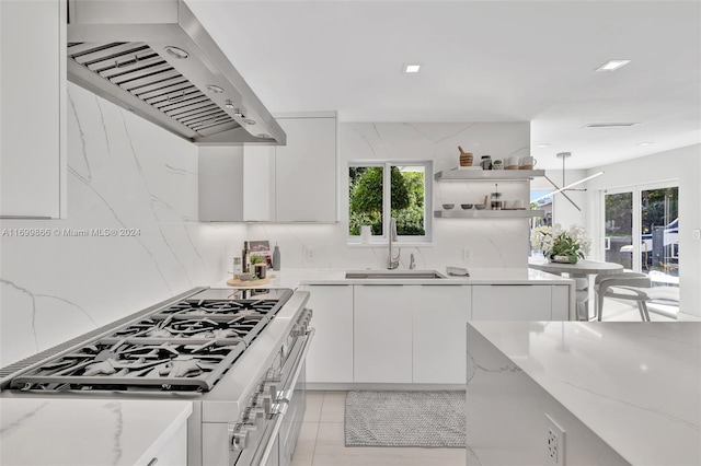 kitchen with extractor fan, light stone countertops, gas stove, and white cabinets