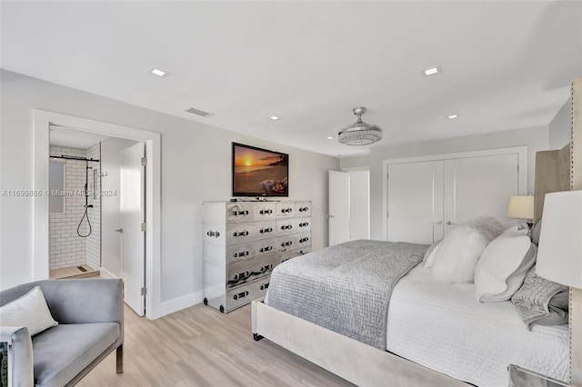 bedroom with a closet, ensuite bath, and light hardwood / wood-style flooring