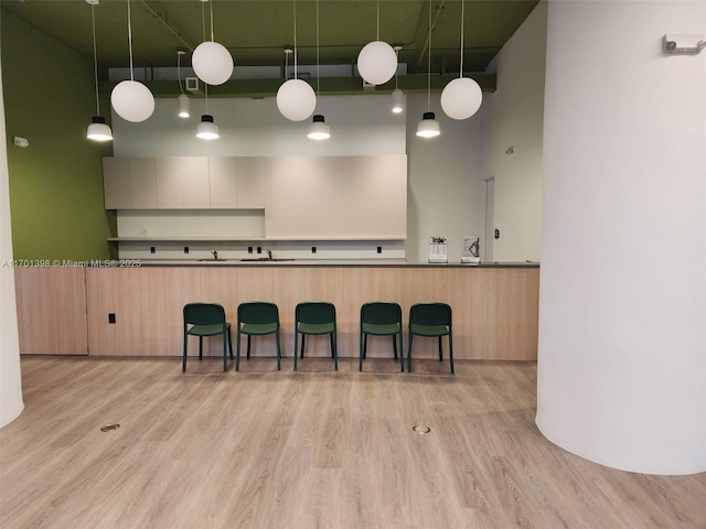 kitchen with dark countertops, a high ceiling, a kitchen bar, and wood finished floors