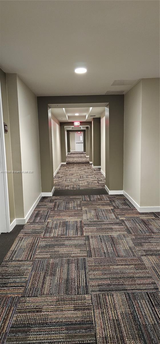 hall featuring carpet floors and baseboards