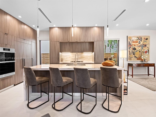 kitchen featuring visible vents, a sink, a kitchen bar, and modern cabinets