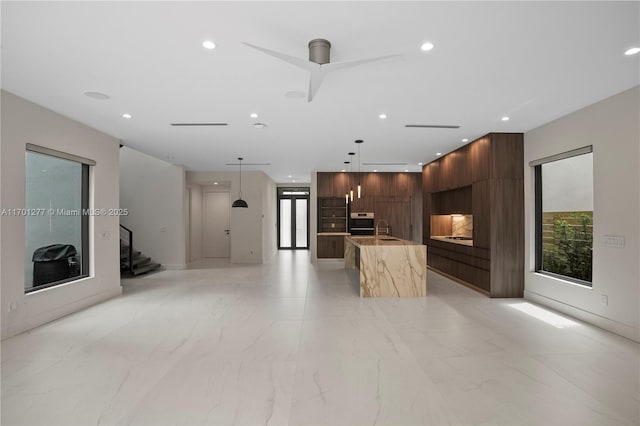 unfurnished living room with stairway, recessed lighting, marble finish floor, and a sink