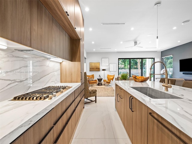 kitchen featuring light stone countertops, modern cabinets, open floor plan, and a sink