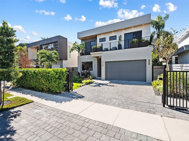 modern home featuring a gate, stucco siding, a balcony, and an attached garage