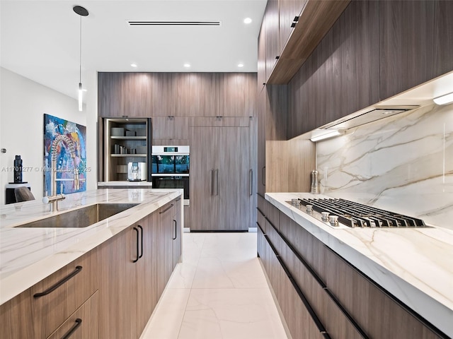 kitchen with light stone counters, double wall oven, a sink, marble finish floor, and modern cabinets