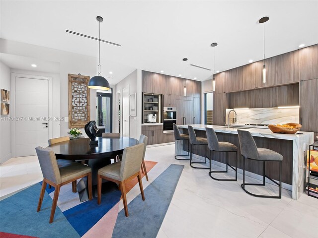 kitchen featuring double wall oven, a sink, marble finish floor, light stone countertops, and modern cabinets