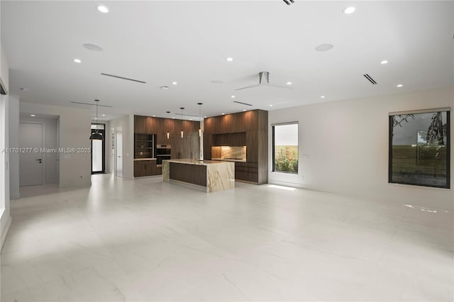 unfurnished living room with recessed lighting, marble finish floor, and a sink