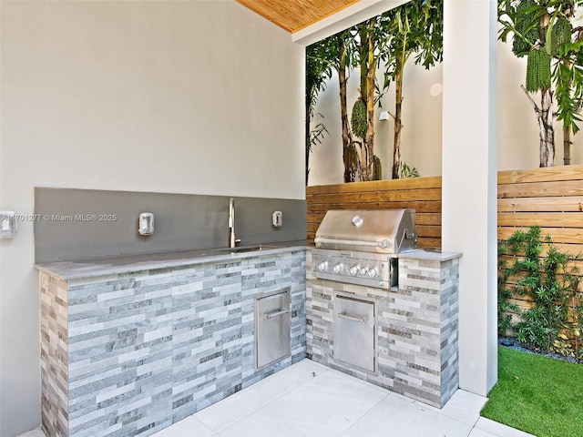 view of patio / terrace featuring fence, an outdoor kitchen, a sink, and area for grilling