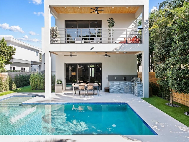 back of property featuring stucco siding, area for grilling, a ceiling fan, fence, and a balcony