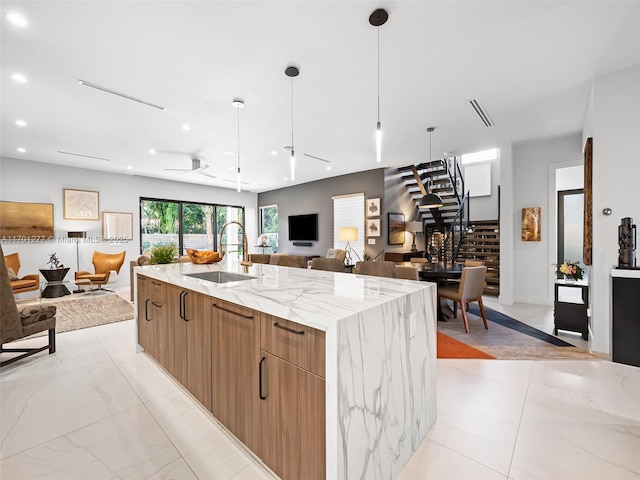 kitchen featuring light stone counters, a spacious island, a sink, open floor plan, and modern cabinets