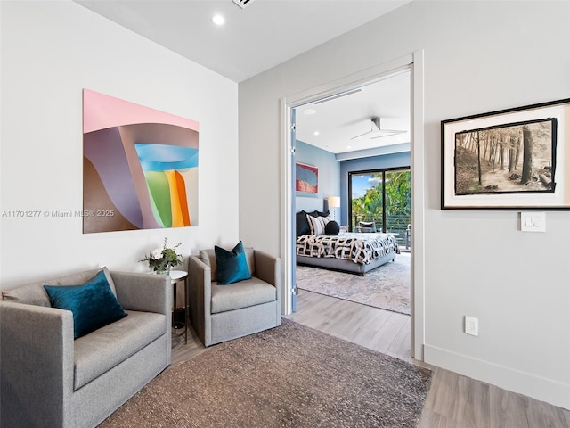 living area with baseboards, wood finished floors, and recessed lighting