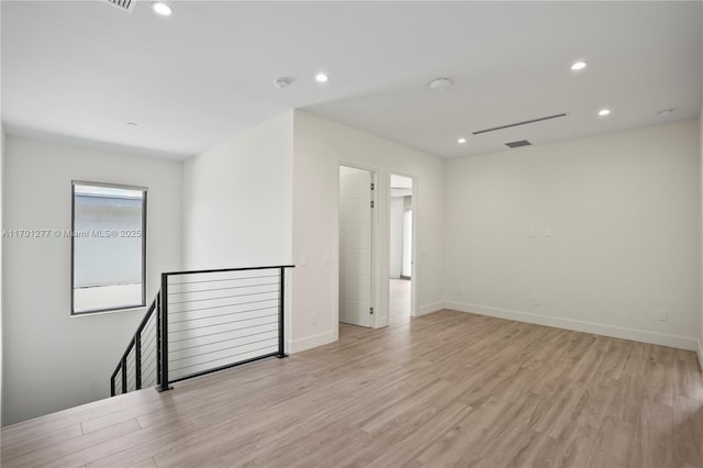 empty room featuring recessed lighting, light wood finished floors, and baseboards