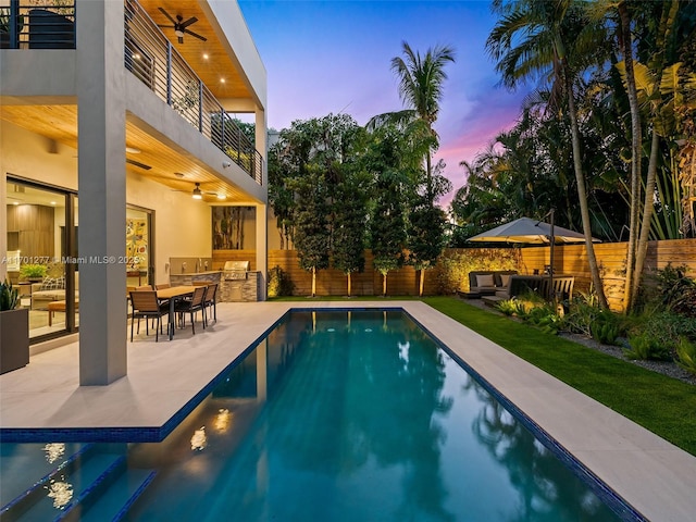 pool at dusk featuring a patio area, ceiling fan, a fenced backyard, and area for grilling