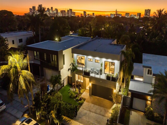 view of front facade featuring a balcony, decorative driveway, stucco siding, a city view, and a garage