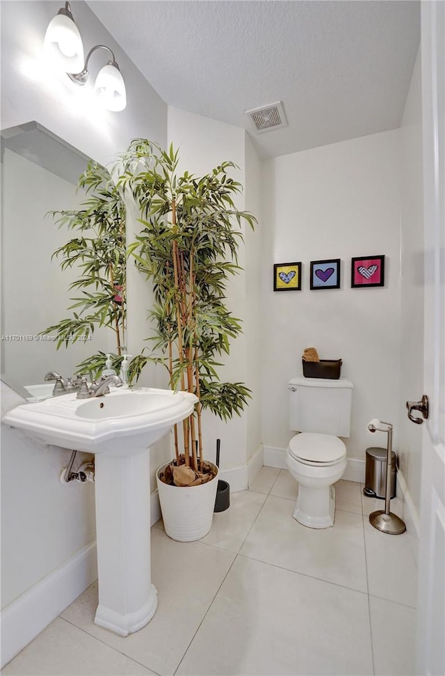 bathroom with tile patterned flooring, toilet, and a textured ceiling