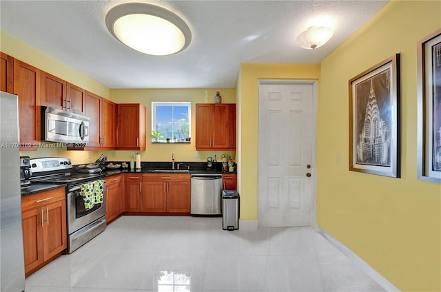 kitchen with a textured ceiling, sink, light tile patterned floors, and stainless steel appliances