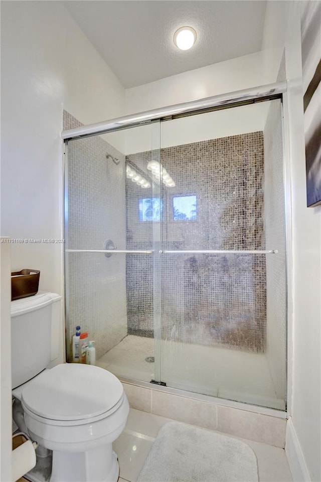 bathroom featuring tile patterned floors, a shower with shower door, and toilet