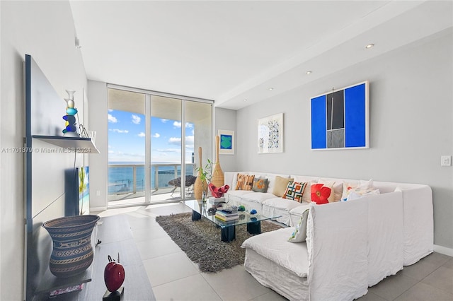 living room featuring tile patterned flooring, floor to ceiling windows, and a water view