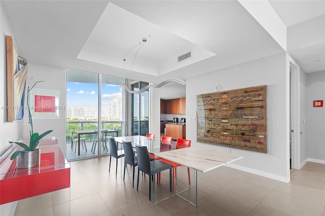 dining space featuring a raised ceiling and a wall of windows