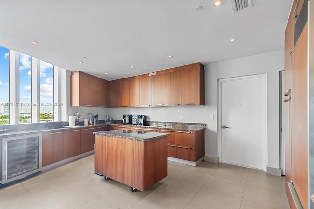 kitchen featuring wine cooler, a kitchen island, dark stone counters, and light tile patterned floors