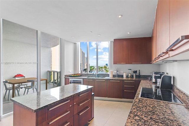 kitchen featuring a center island, dark stone counters, black electric stovetop, sink, and wine cooler