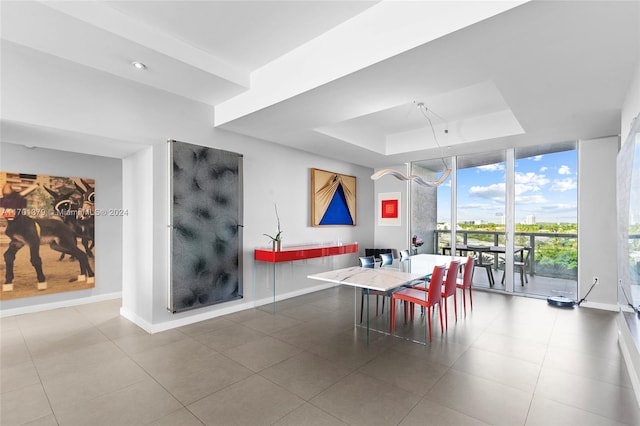 dining area with floor to ceiling windows and a raised ceiling