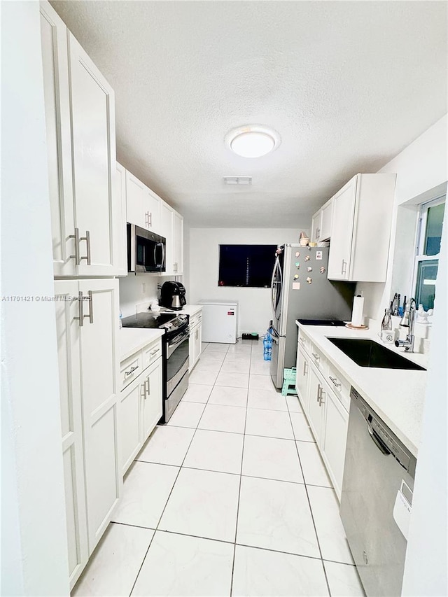 kitchen with sink, a textured ceiling, stainless steel appliances, and white cabinets