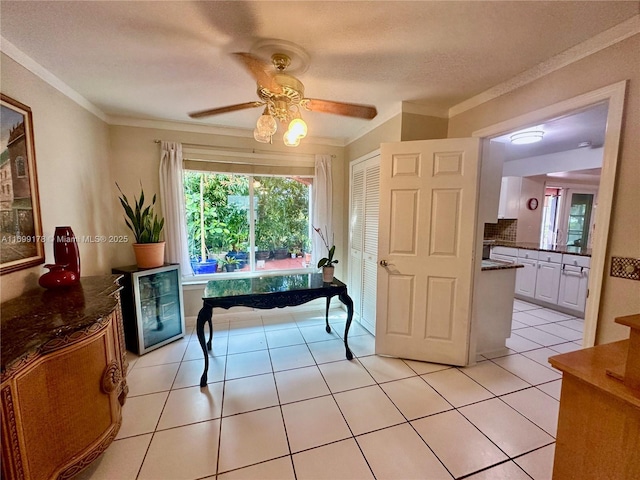 tiled dining space featuring ceiling fan, ornamental molding, a textured ceiling, and wine cooler