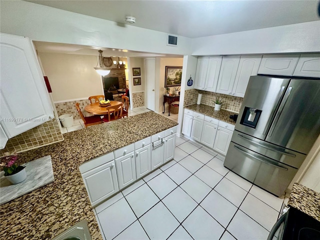 kitchen with tasteful backsplash, white cabinets, stainless steel fridge, decorative light fixtures, and light tile patterned floors